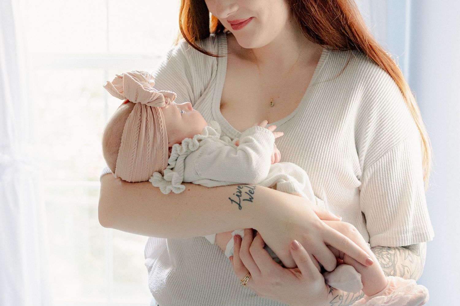 Close-up of someone wearing a cream sweater holding a small baby.