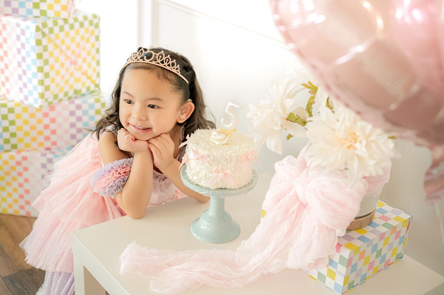 A festive birthday setup with pink decorations and a sparkly tiara against a light background.