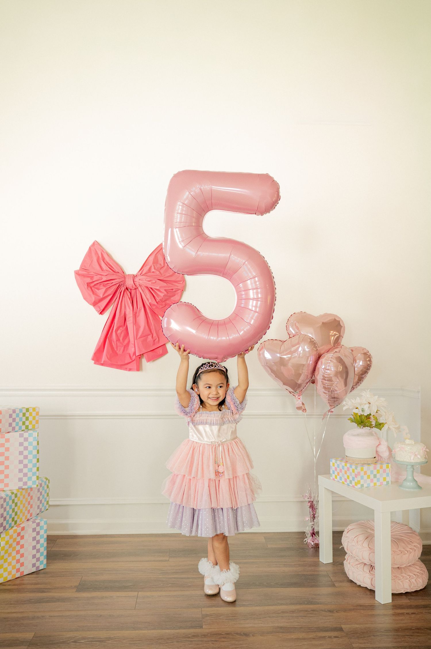 A pink and white themed birthday setup with large number 5 balloon and decorative bows.