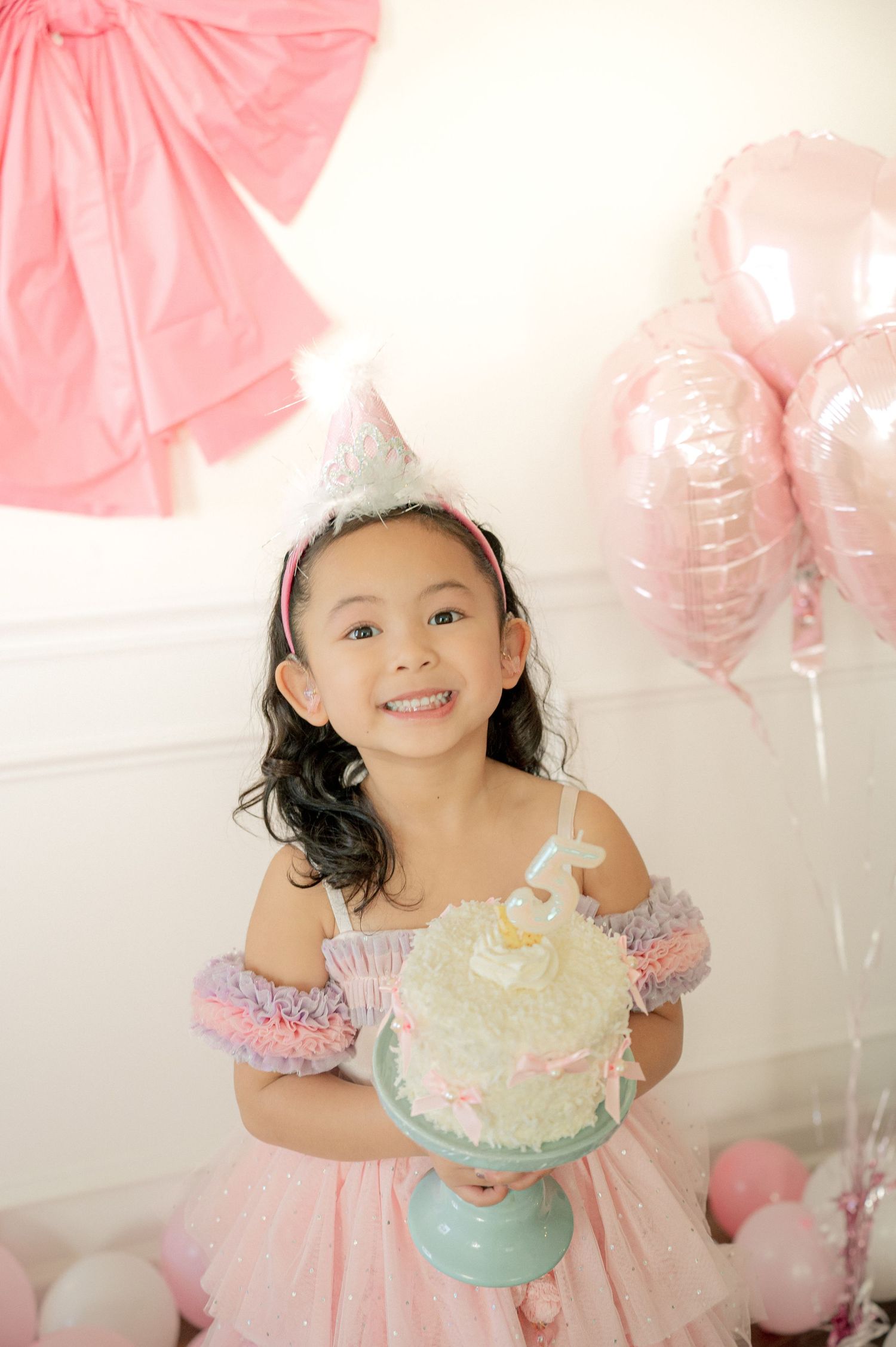 A birthday celebration with pink balloons and a small turquoise cake.