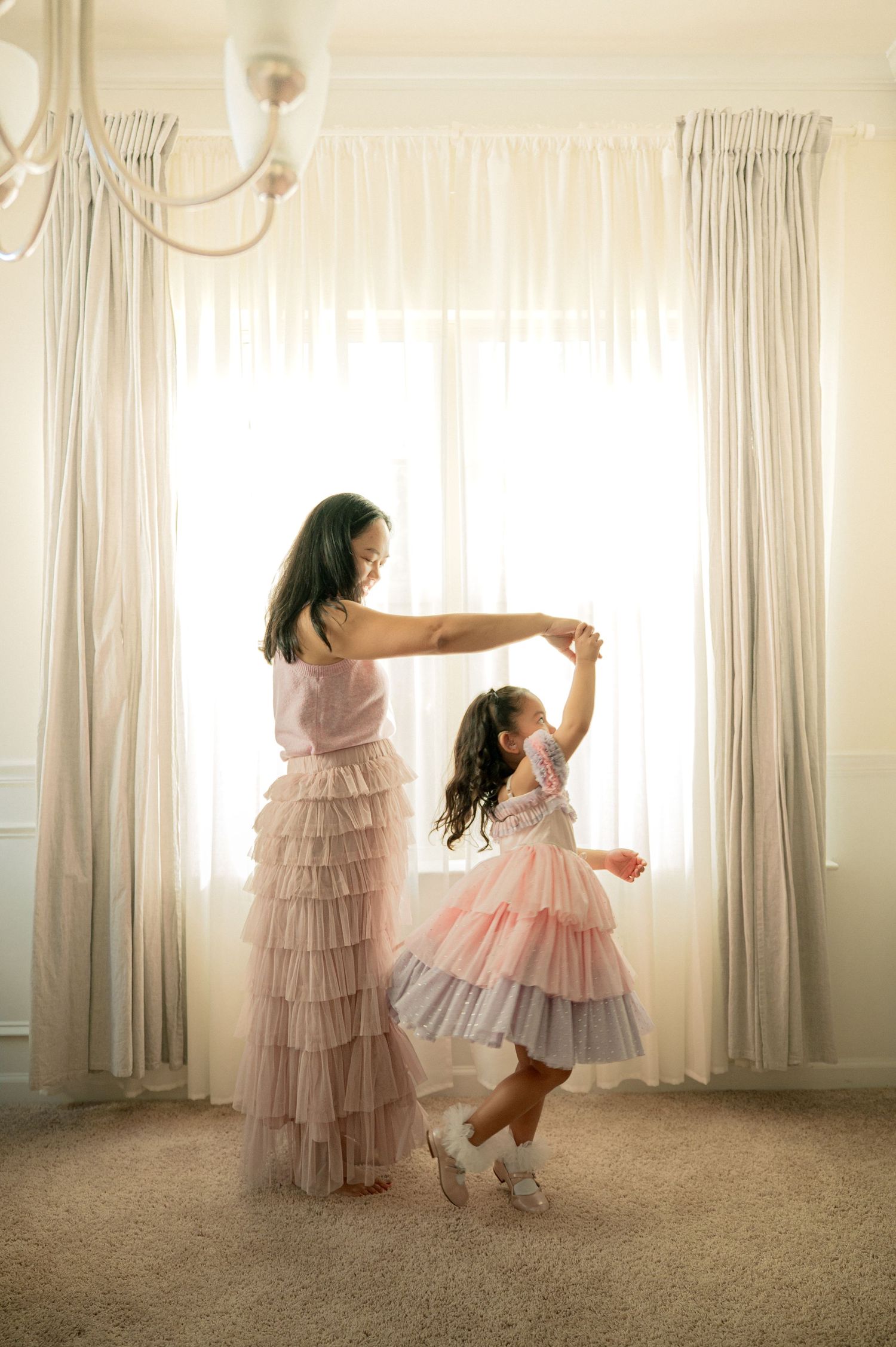A sequence of dance-like movements in a sunlit room with flowing curtains and a ruffled pink dress.