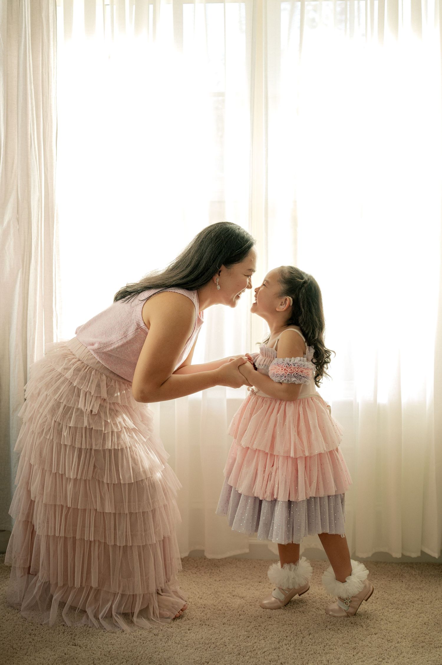 A sweet moment captured in soft lighting with matching pink tulle dresses.