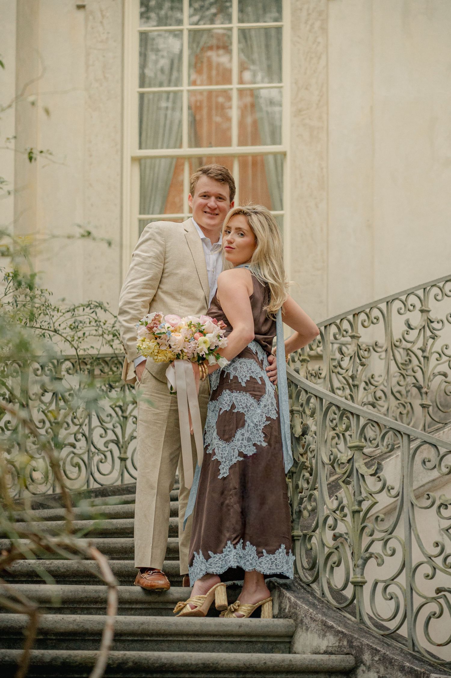 Romantic photoshoot on vintage mansion steps with elegant architectural details.