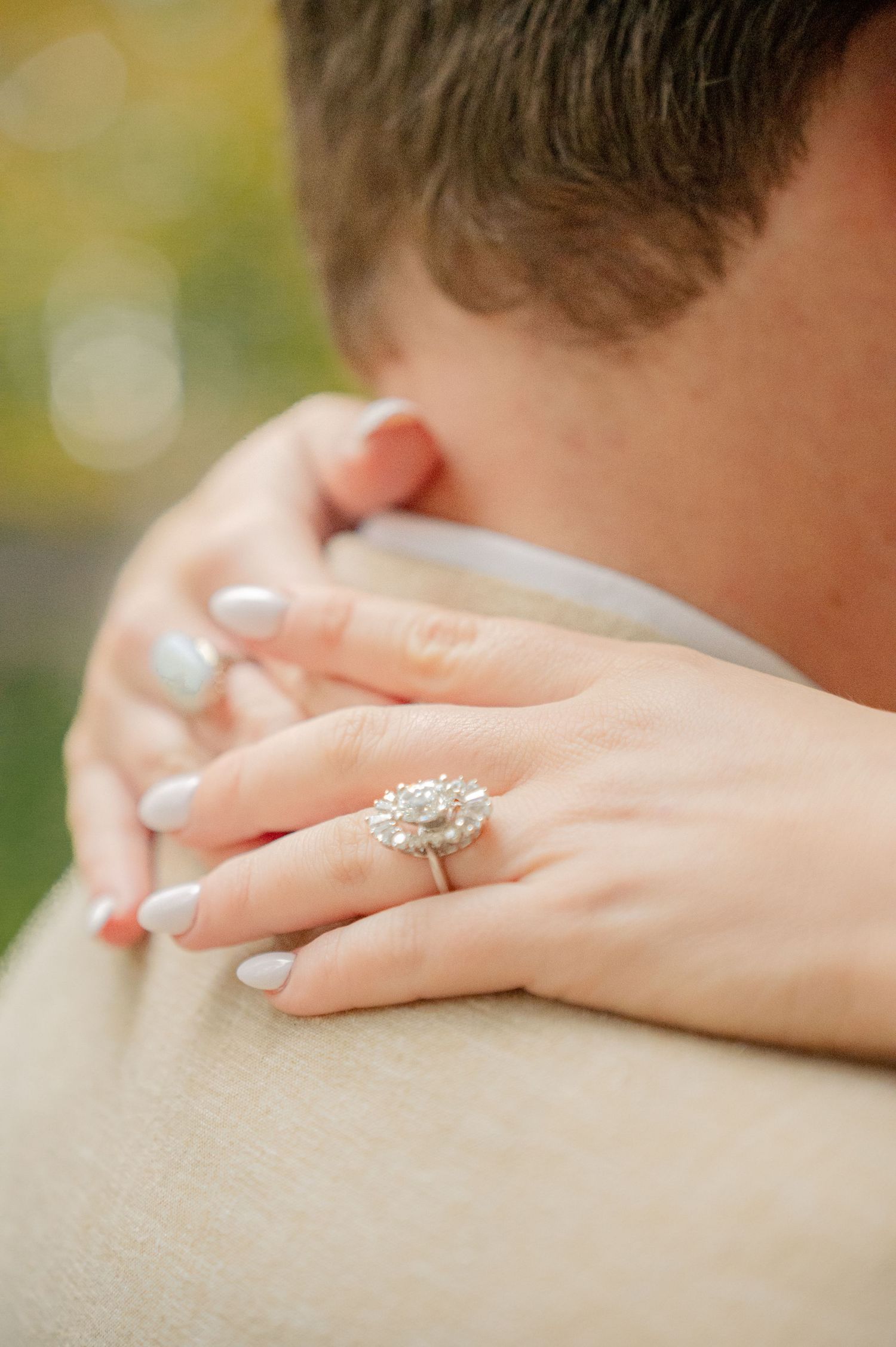Close-up of diamond engagement ring with hands embracing.