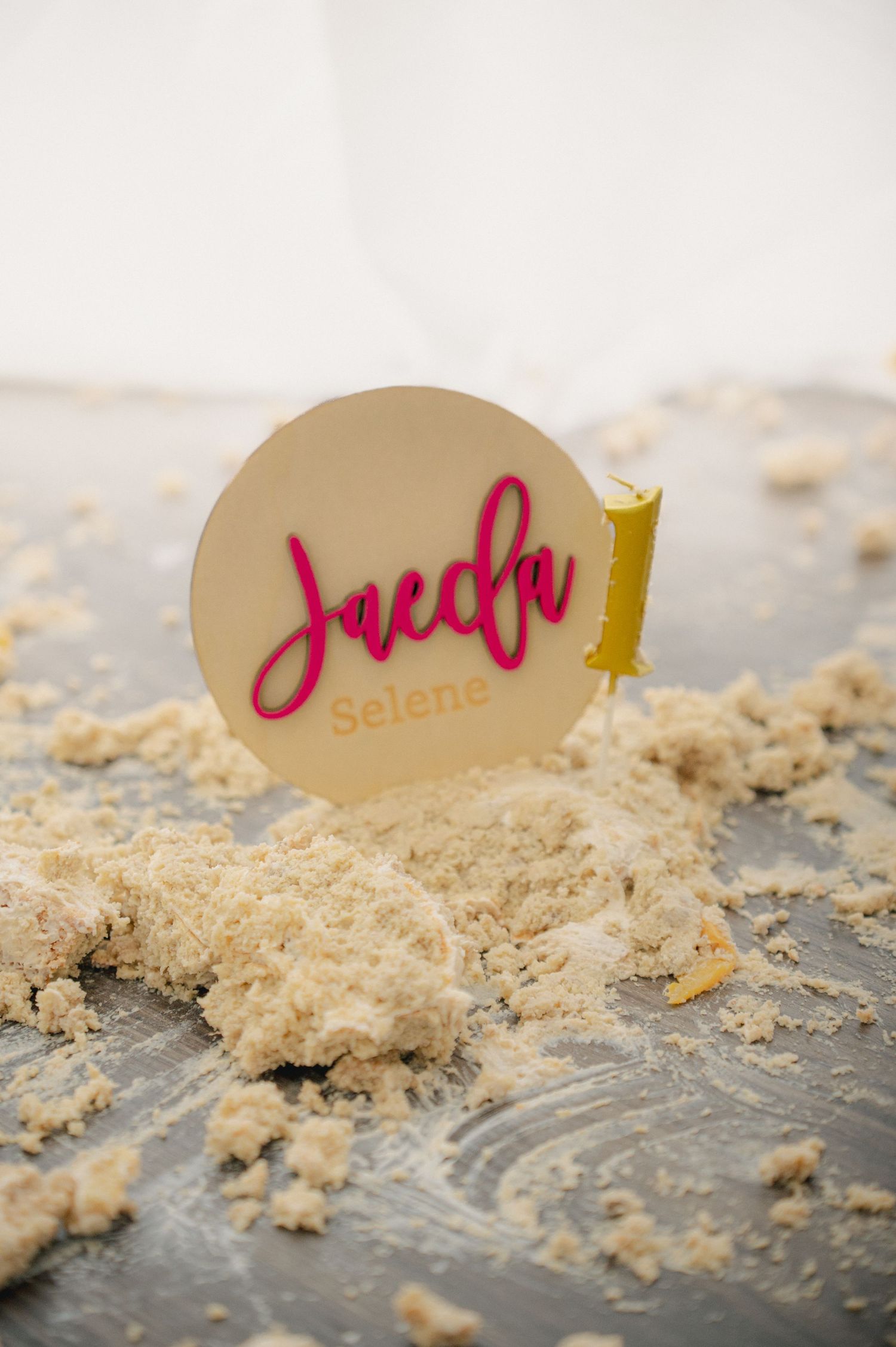 Close-up of cake crumbs scattered on a dark surface with name tags visible.