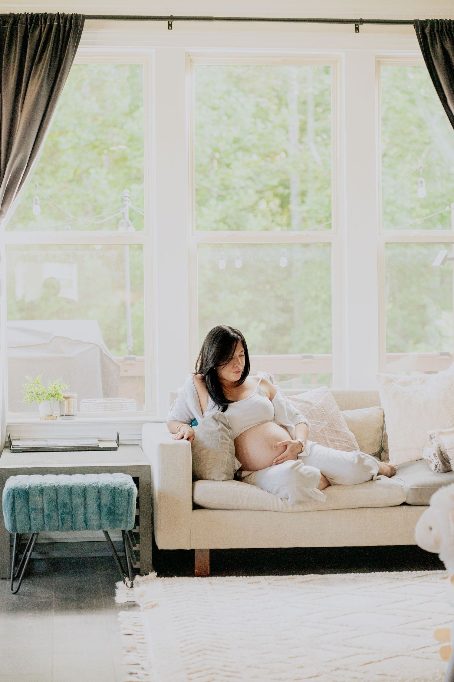 Expectant mother rests peacefully on couch in sunlit room with modern decor.