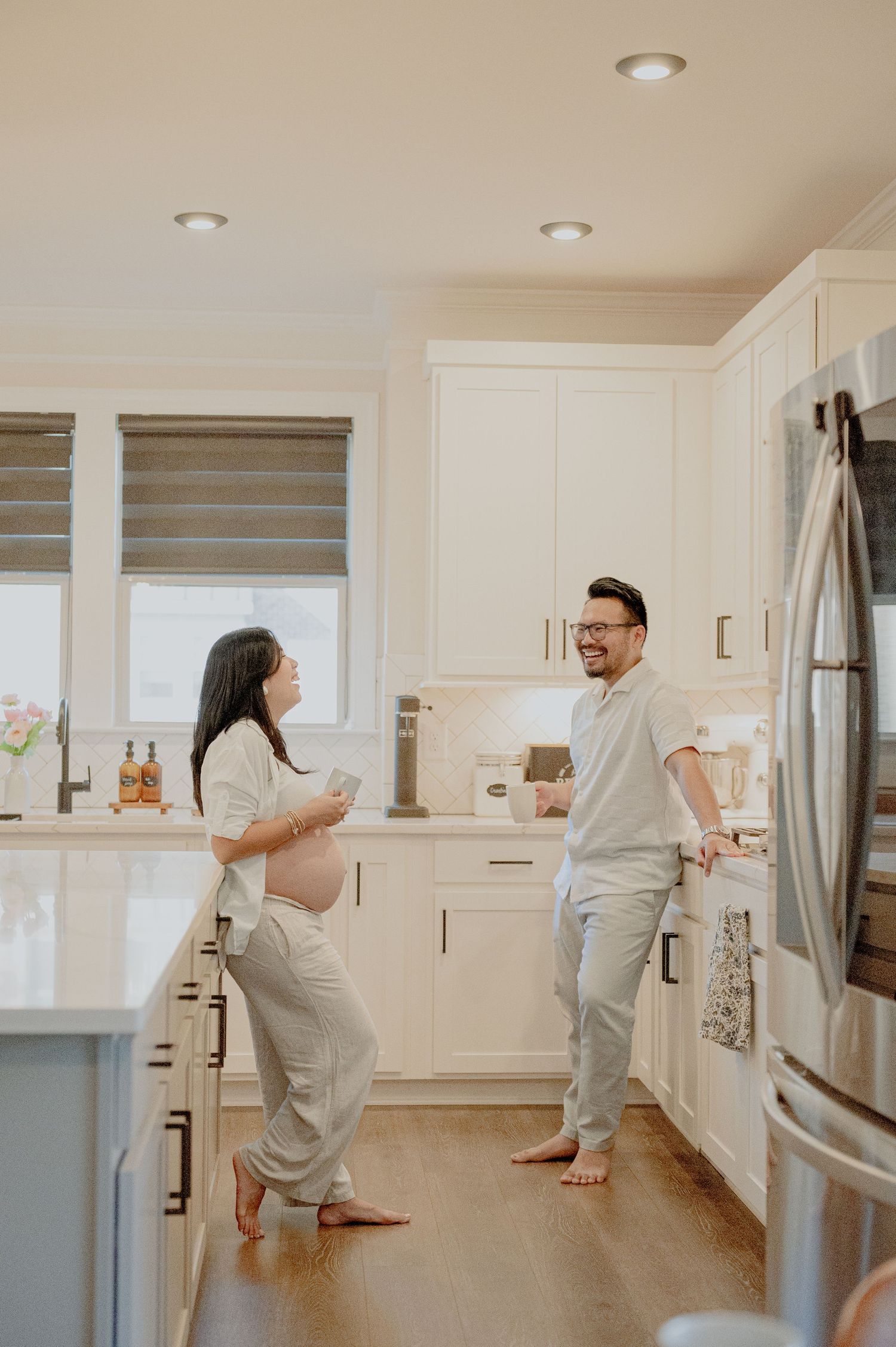 Dancing together in bright modern kitchen during pregnancy photoshoot.
