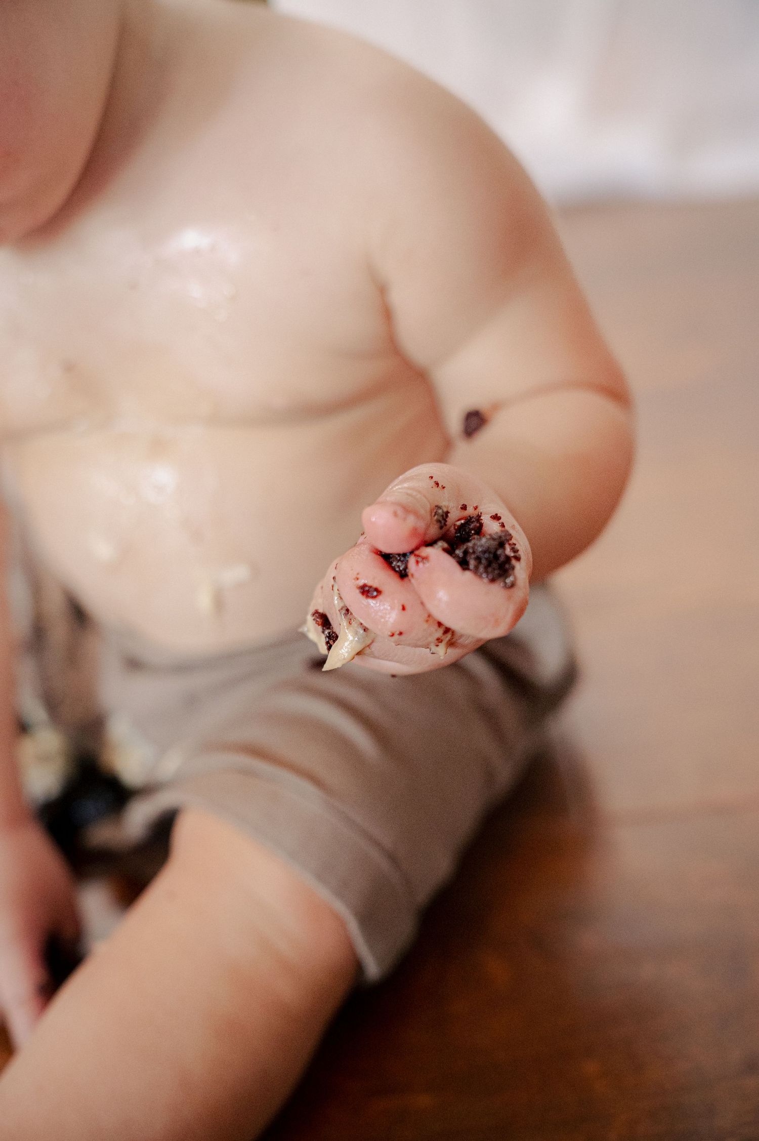 Close-up of baby's hands and tummy covered in cake and frosting.