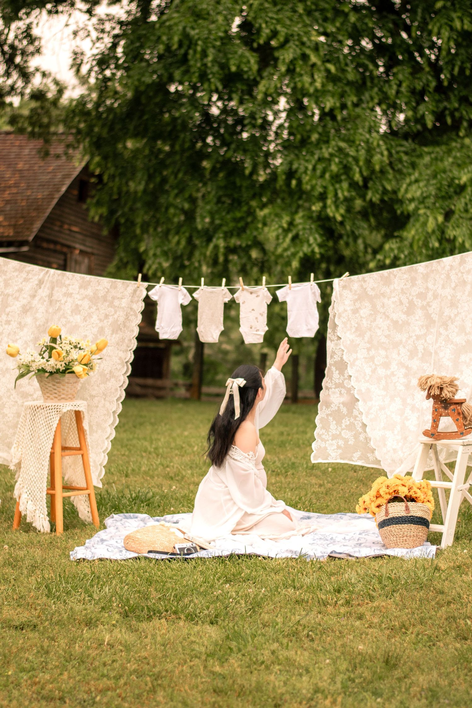 Garden maternity photography featuring white lace clotheslines and rustic outdoor props.