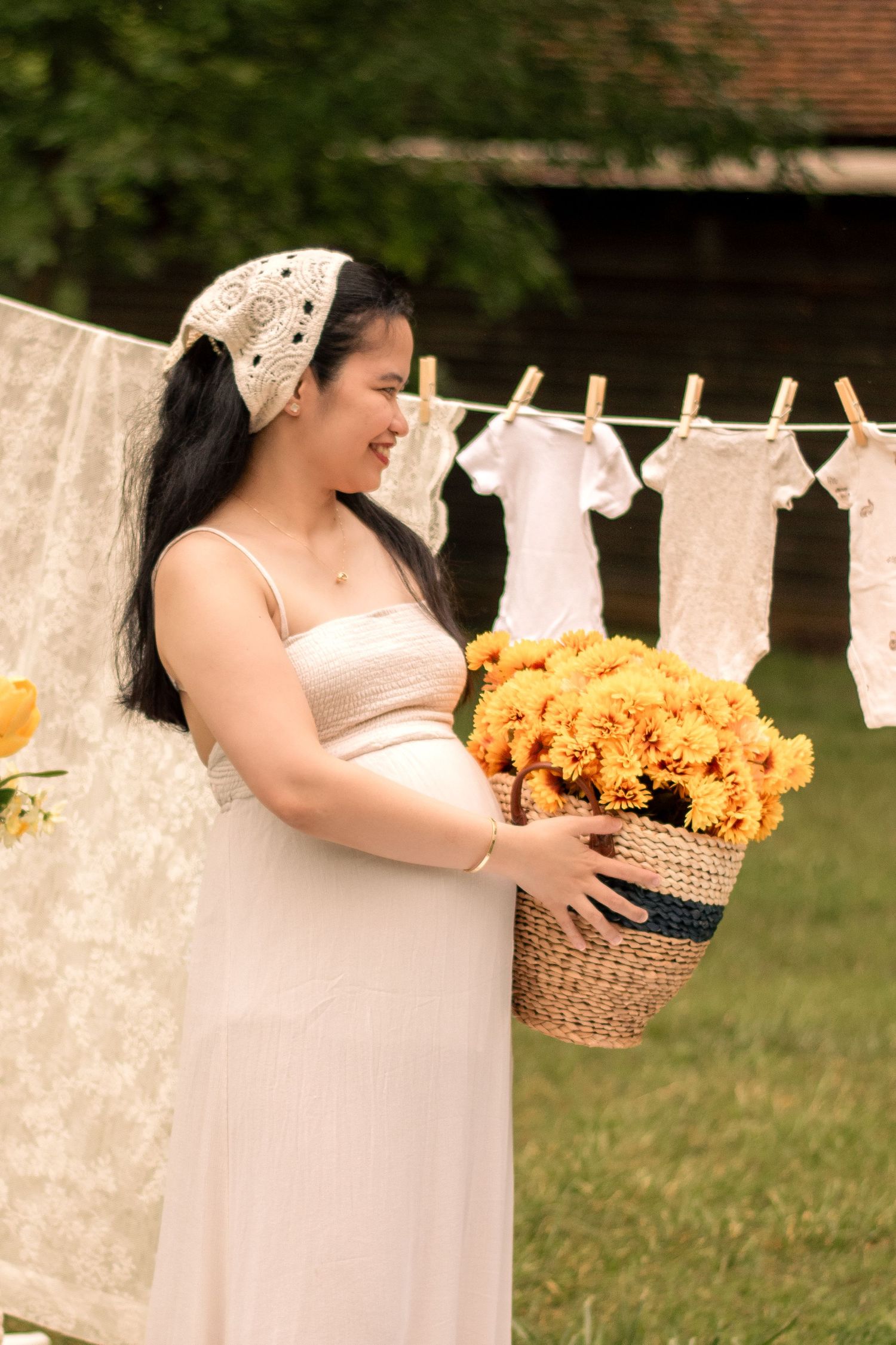 Outdoor maternity scene with sunflowers and white linens creating a vintage laundry day aesthetic.
