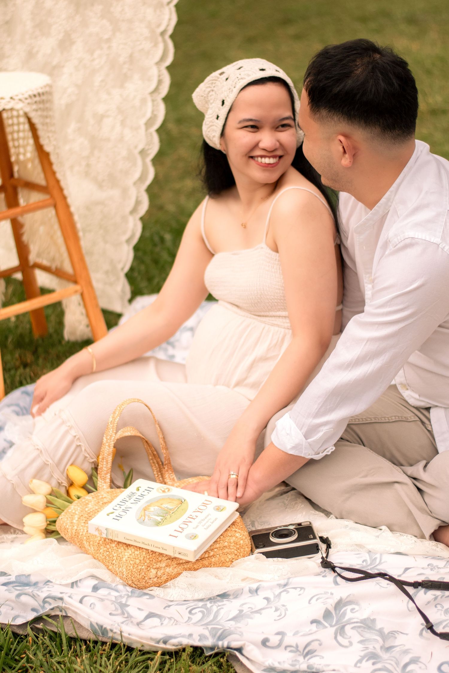 Intimate maternity moment captured on white lace blanket with vintage props and decorations.