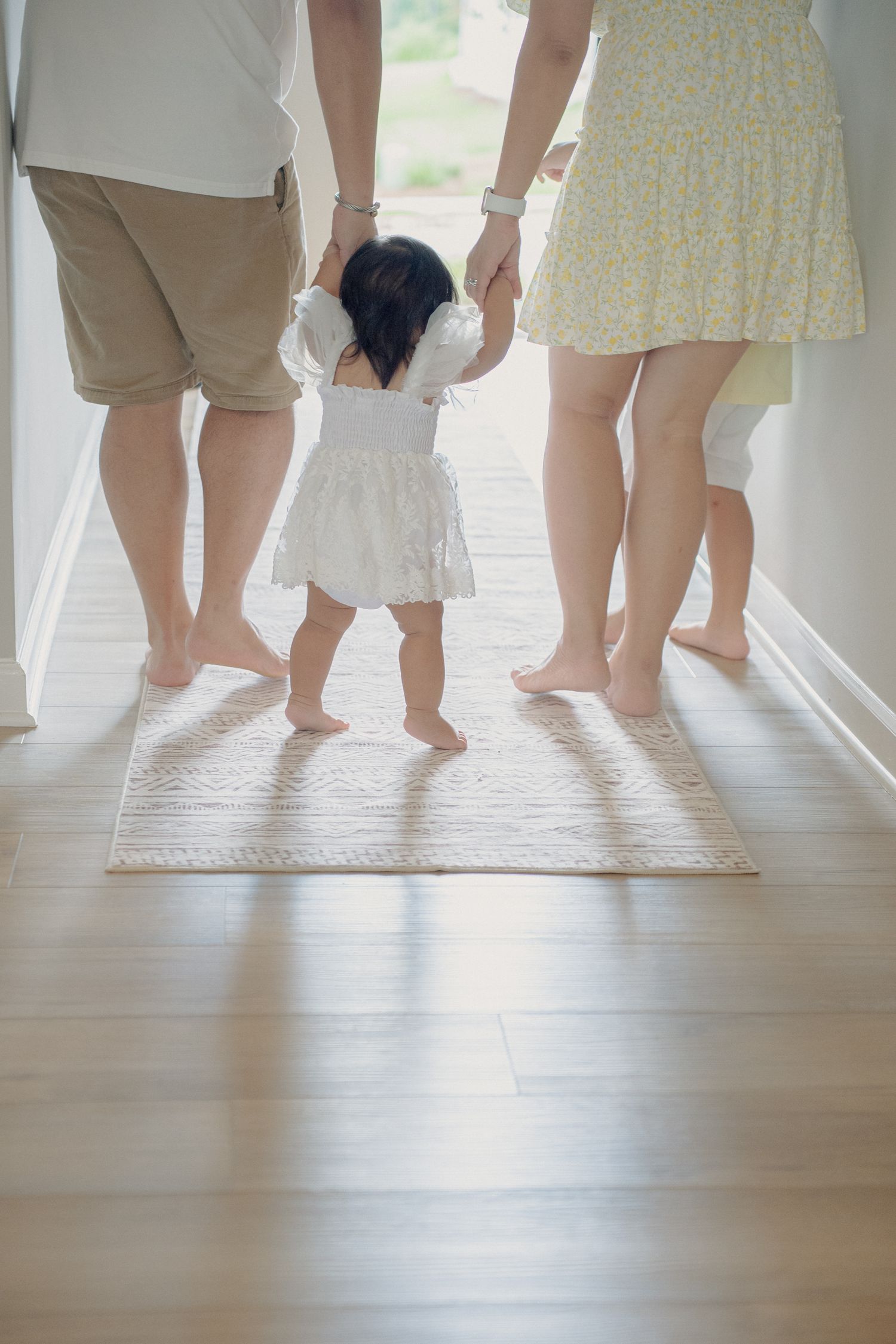 Low angle view of family members' feet and legs walking together on light wooden flooring.