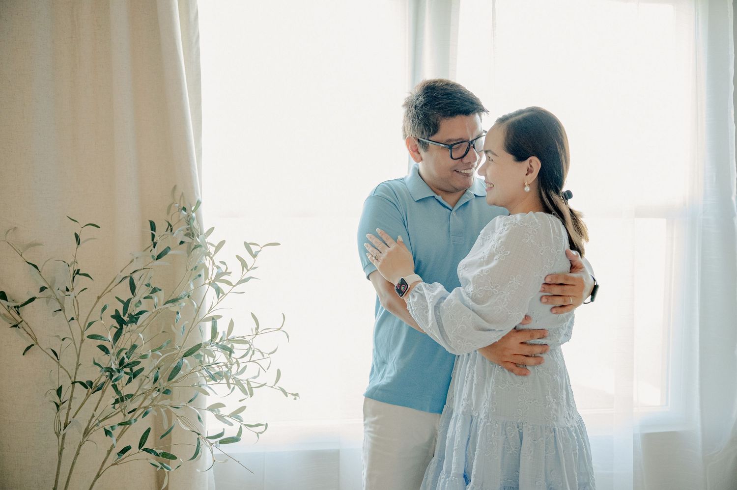 Candid family moments captured against a white backdrop with natural window lighting.