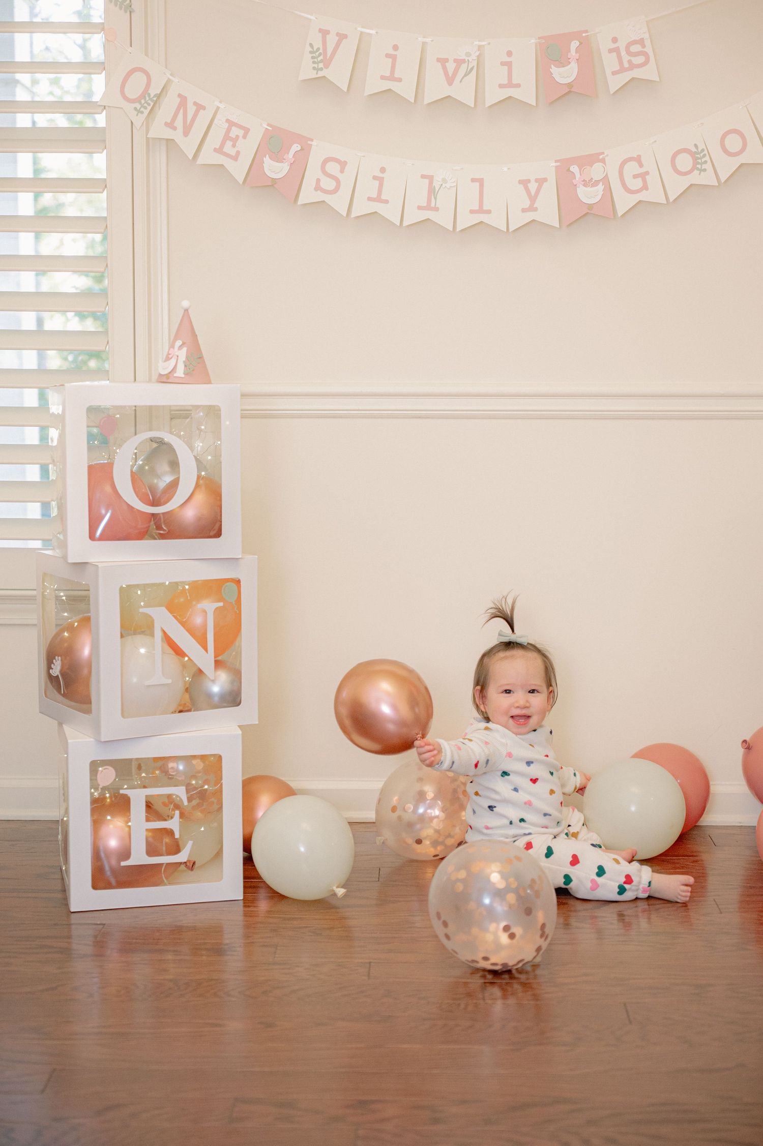 Pink and white party decorations with balloons and banners set up for a celebration.