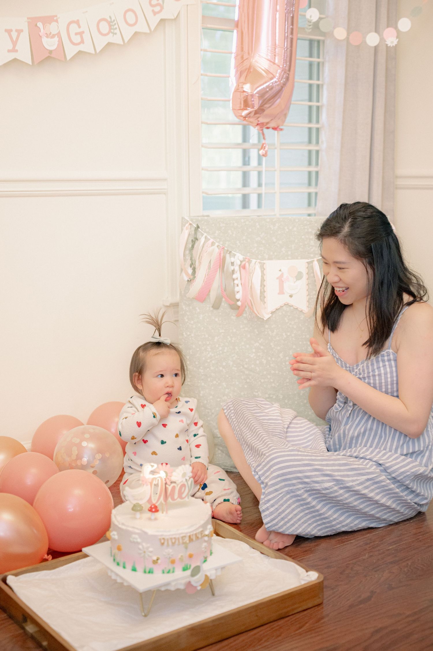 Birthday celebration with cake and pink decorations on wooden table.