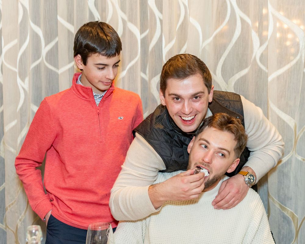 Three friends posing playfully against a patterned wall at a social gathering during engagement party in Westborough, MA.  Event Photograph