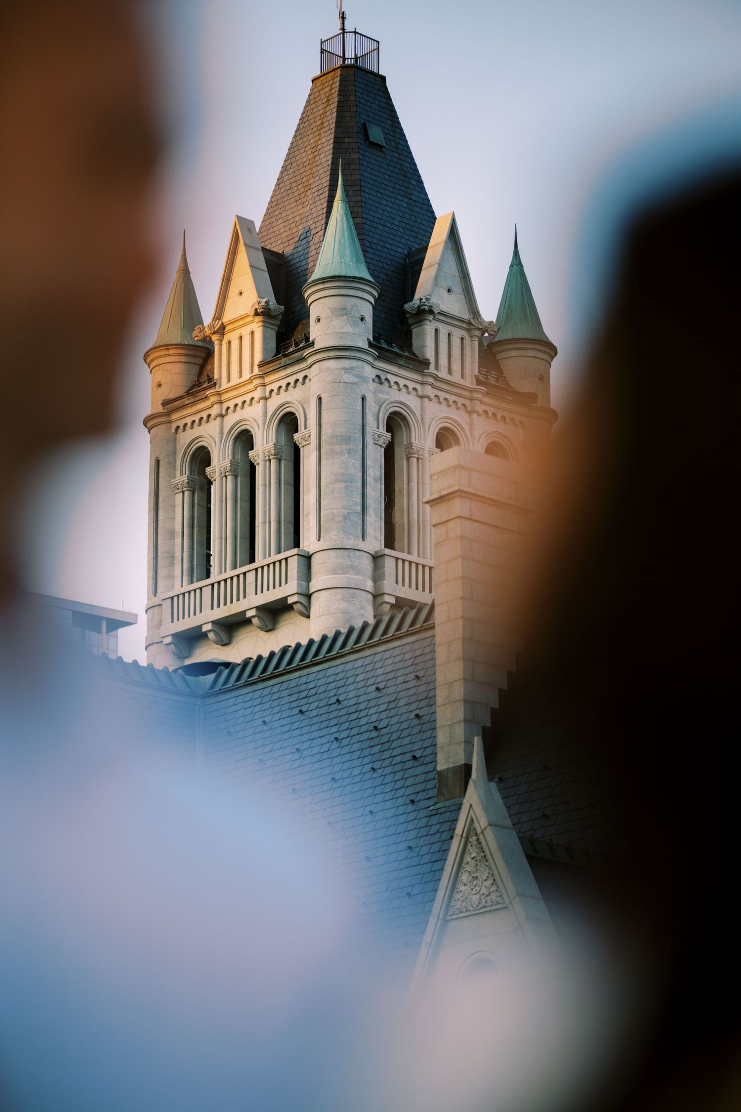 Gothic church tower with ornate spires and arched windows photographed against a soft blurred background.