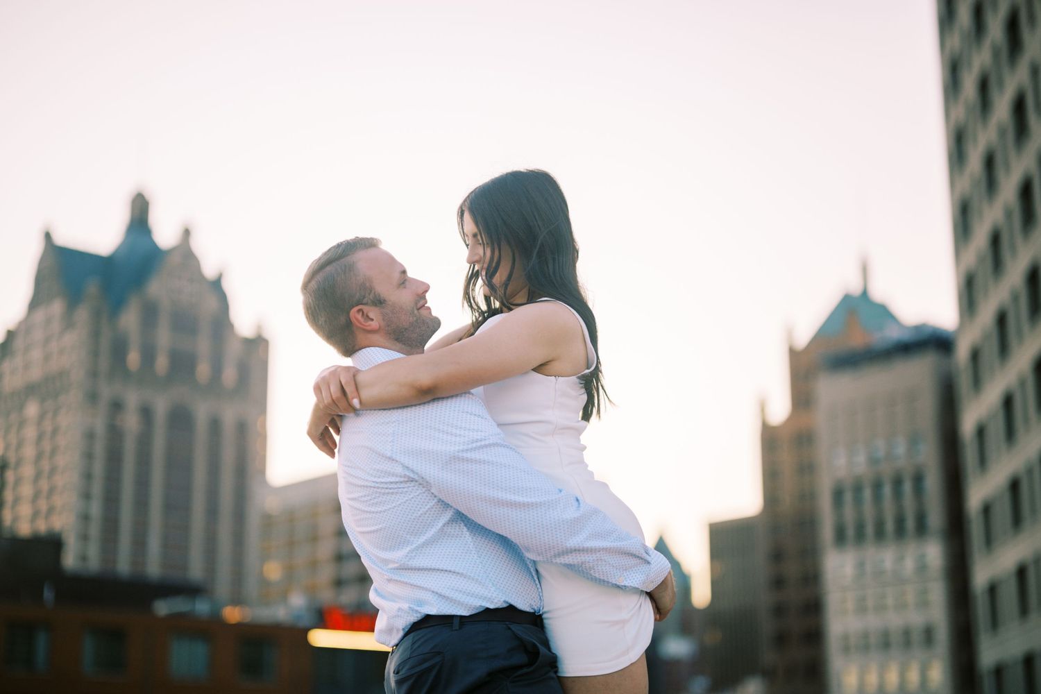 A romantic rooftop embrace with city architecture in the background during golden hour.