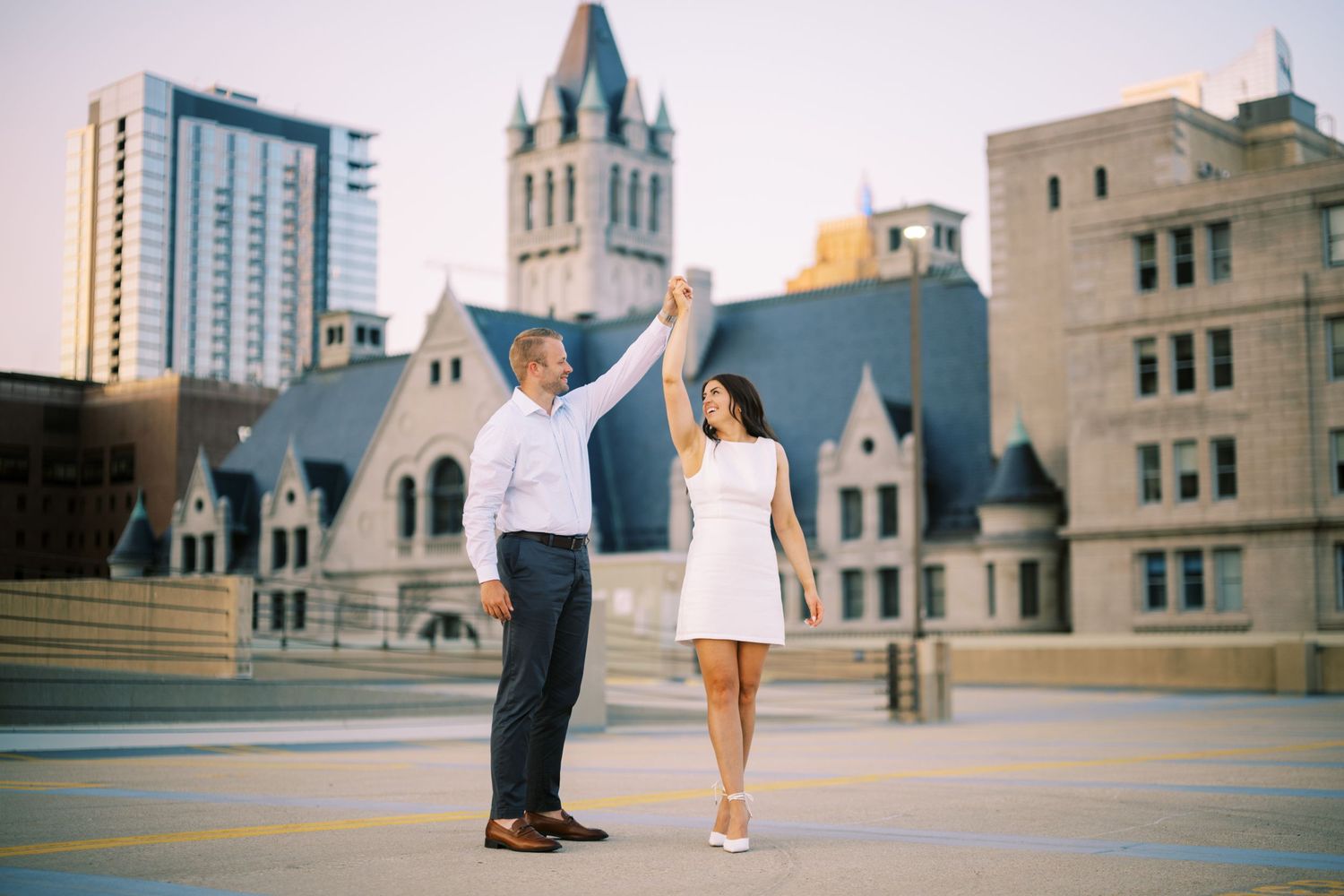 A couple celebrates on a rooftop terrace with historic architecture and city buildings in the background.