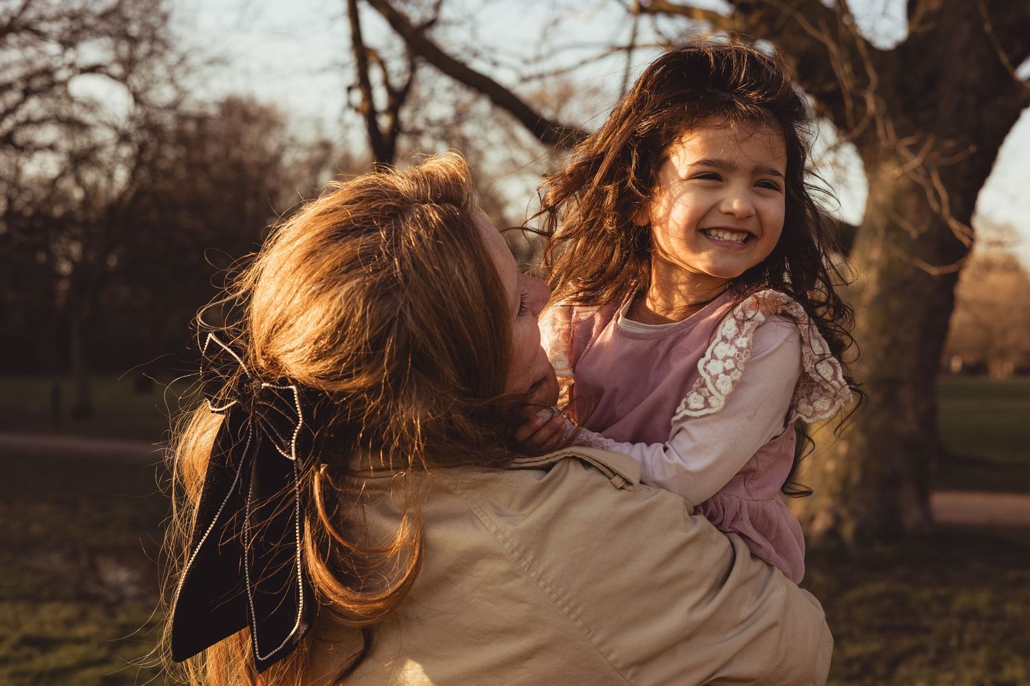 mum and daughter spinning around outdoors, laughing