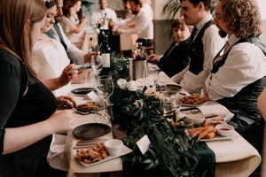 Guests dining at an elegant dinner party with wine and table settings decorated with dark florals.