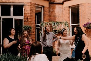 A group of people gathered on an outdoor patio with exposed brick walls enjoying a social event.