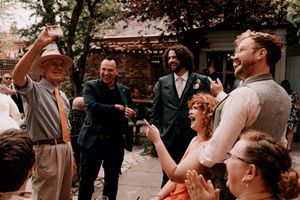 People enjoying a lively moment at an outdoor celebration with laughter and animated gestures in a courtyard setting.