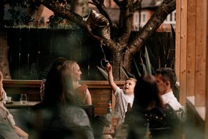Friends enjoying a lively moment together at an outdoor restaurant patio on a warm evening.