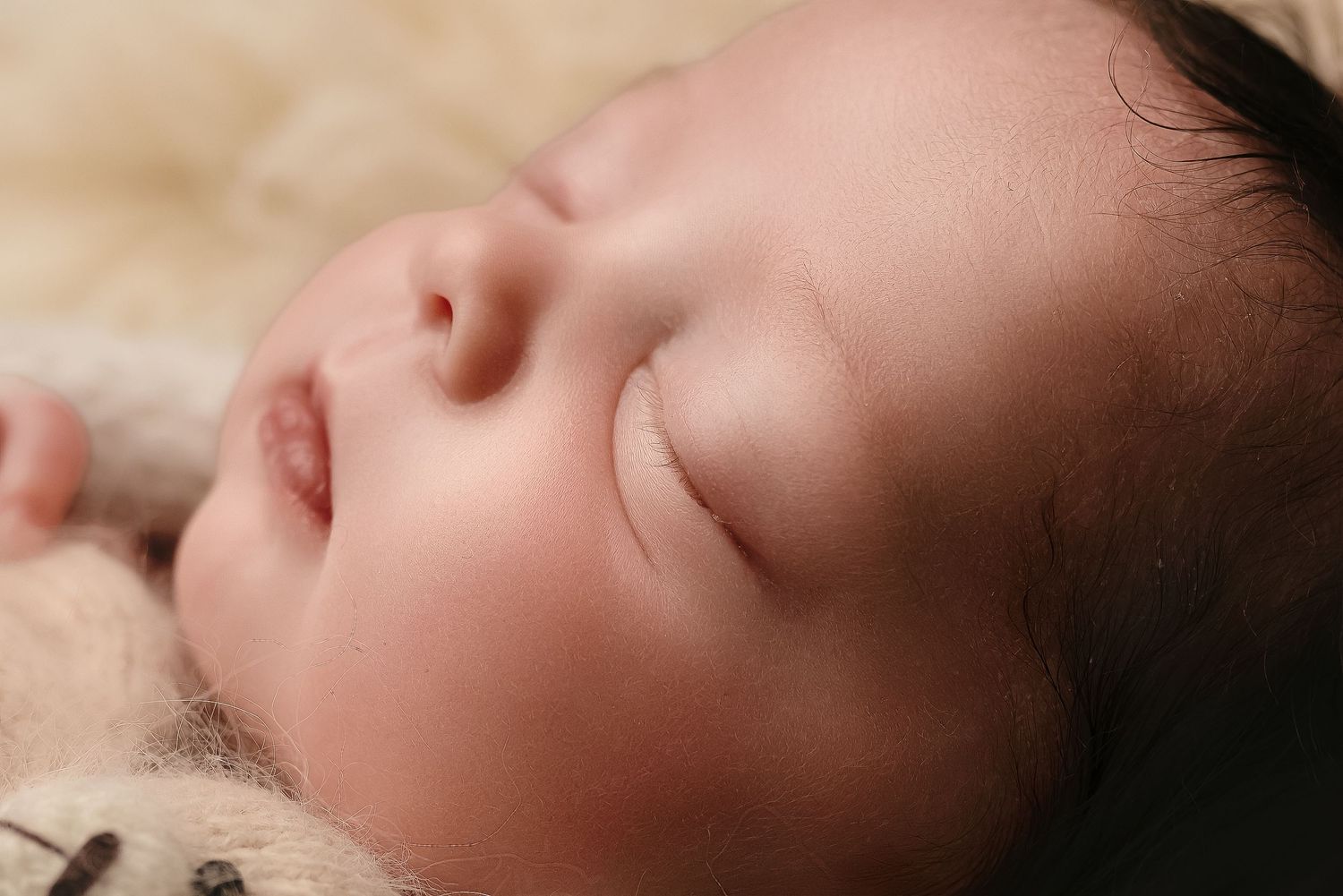 Charlottesville photographer, maternity, family, newborn, close-up shot of baby girl sleeping against warm, neutral background.