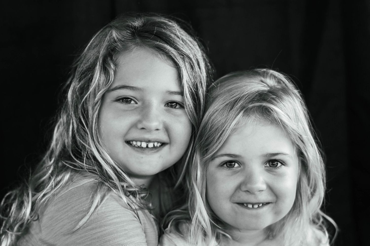 Siblings smiling for a group portrait in an outdoor family session with their school
