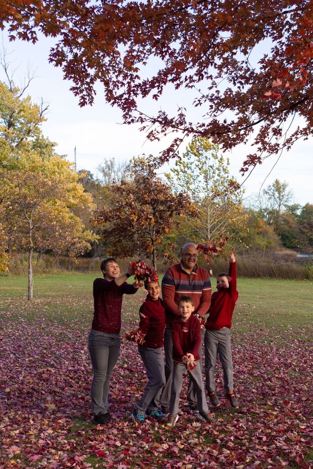 Group photo session in a park with vibrant fall foliage and red leaves on the ground.