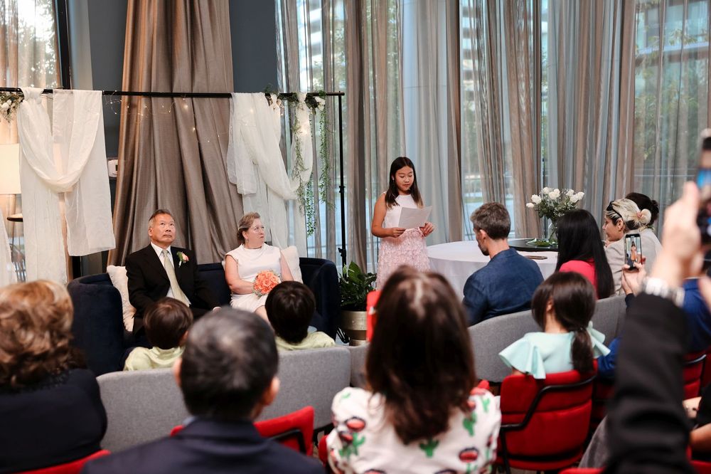 Indoor wedding ceremony with sheer curtains and rows of guests seated in chairs.