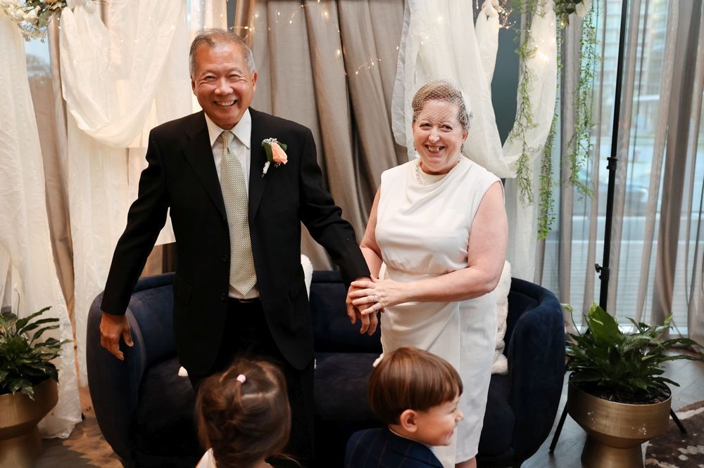 Intimate wedding gathering with decorative white drapes and potted plants.