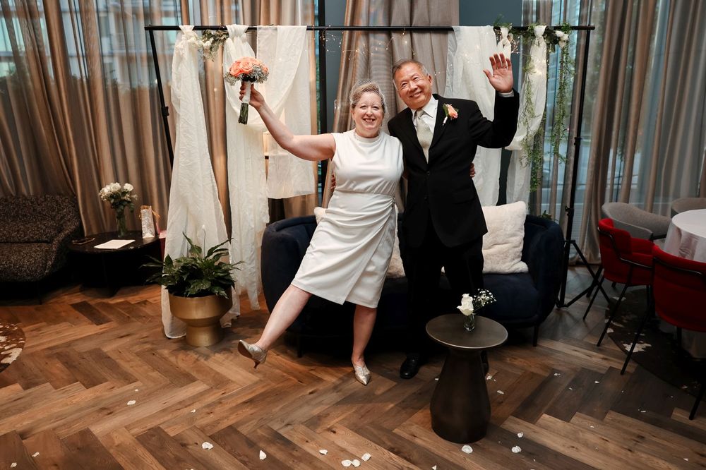 Wedding celebration with dancing and festive expressions on a herringbone wood floor.