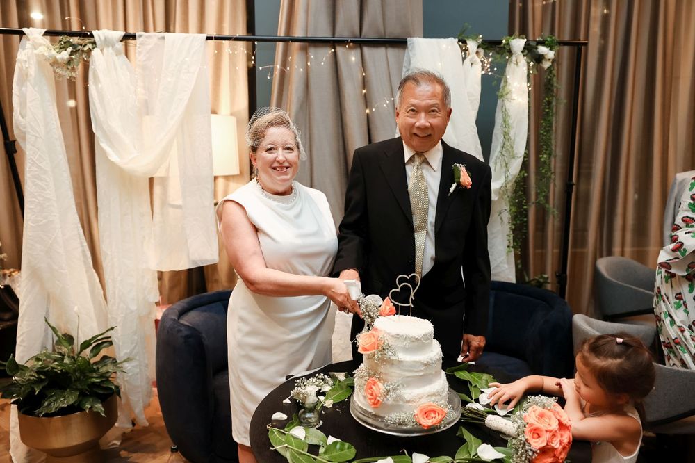 Wedding couple stands behind their decorated cake during the traditional cake cutting ceremony.