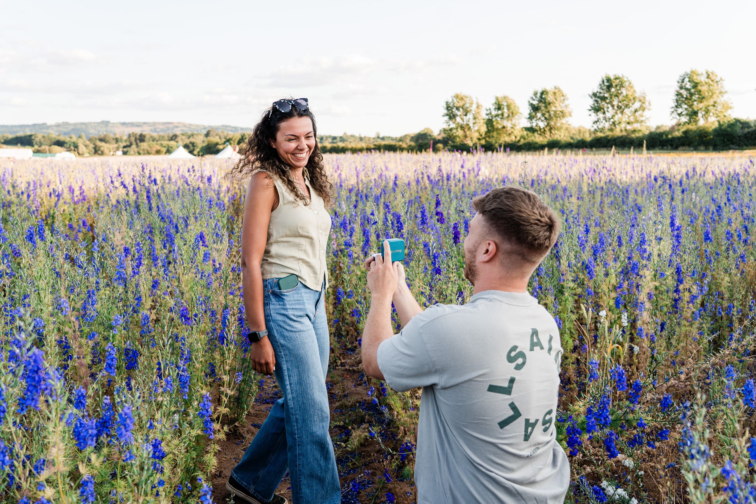 Couple shares intimate moment in field of vibrant purple wildflowers at sunset.