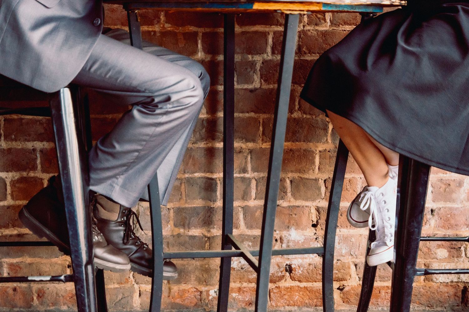 Feet of couple sitting across from each other at metal table in downtown Greer, South Carolina at storytelling couples session
