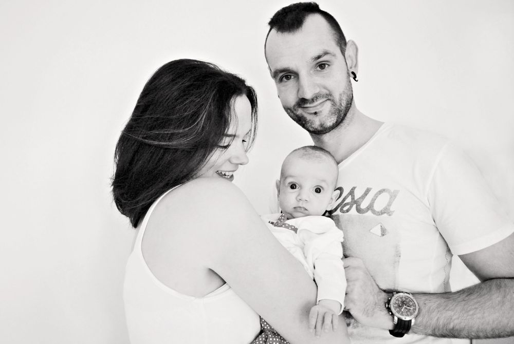 A tender black and white family portrait showing affectionate moments with a baby.