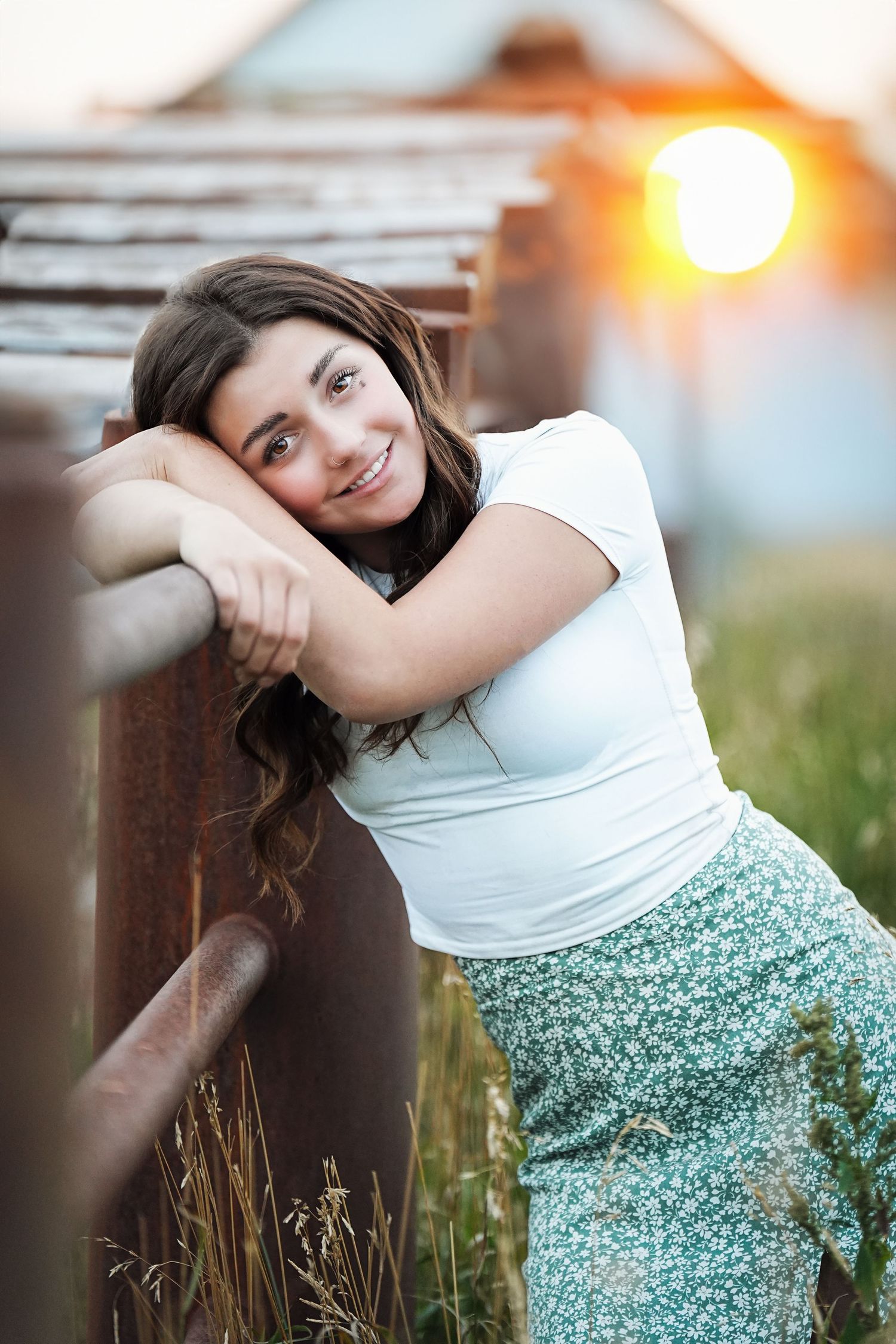 Portrait against rustic fence at golden hour with soft lighting.