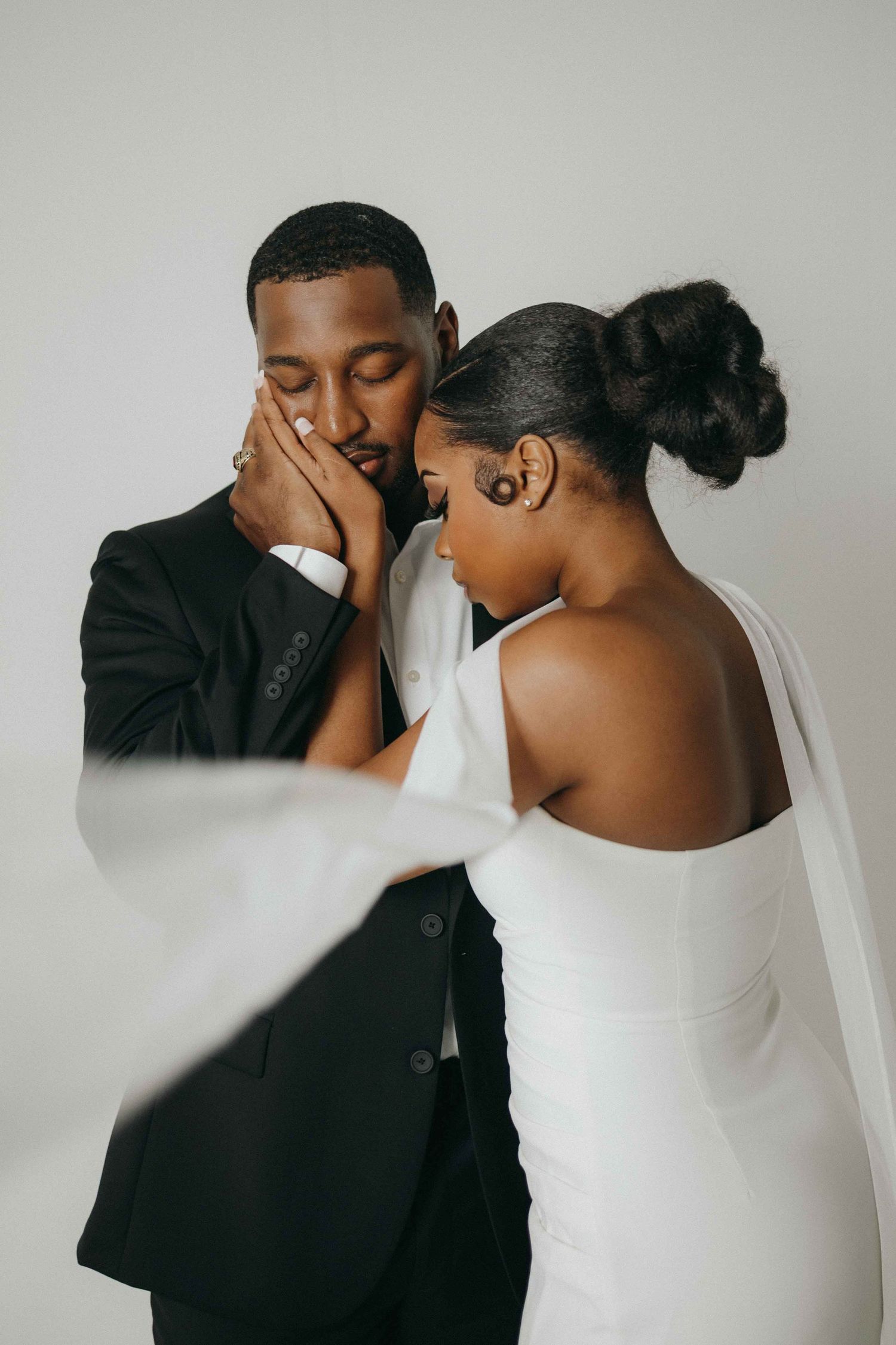 An intimate wedding portrait against a white background capturing a tender emotional moment.