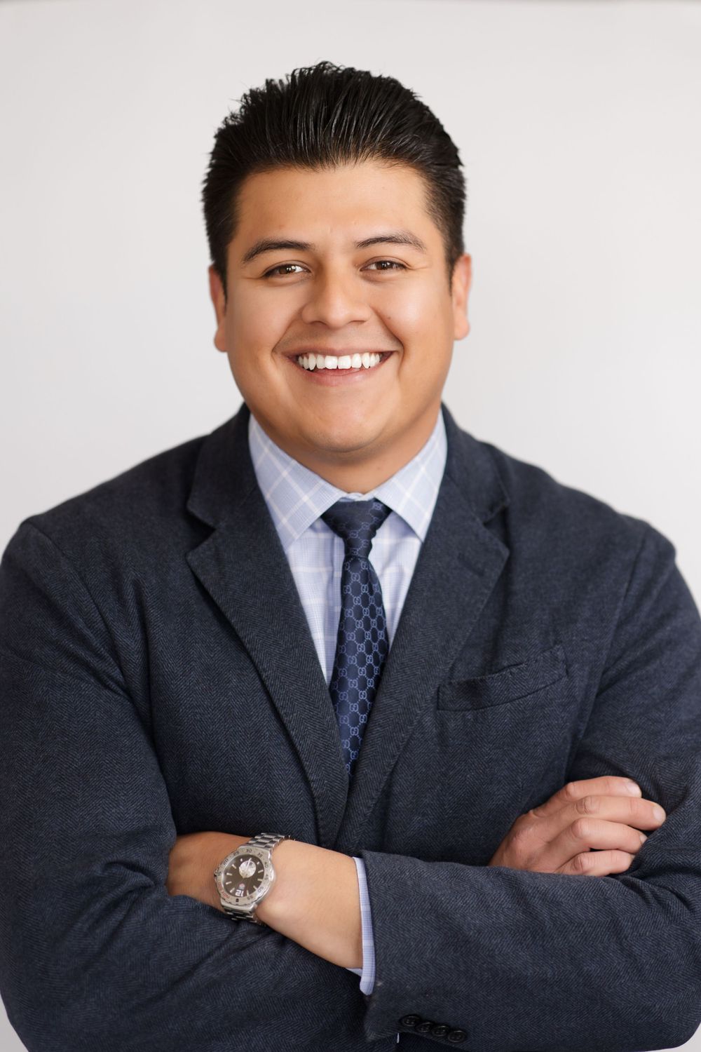 Professional business portrait of a person in a dark suit and tie against a light background.