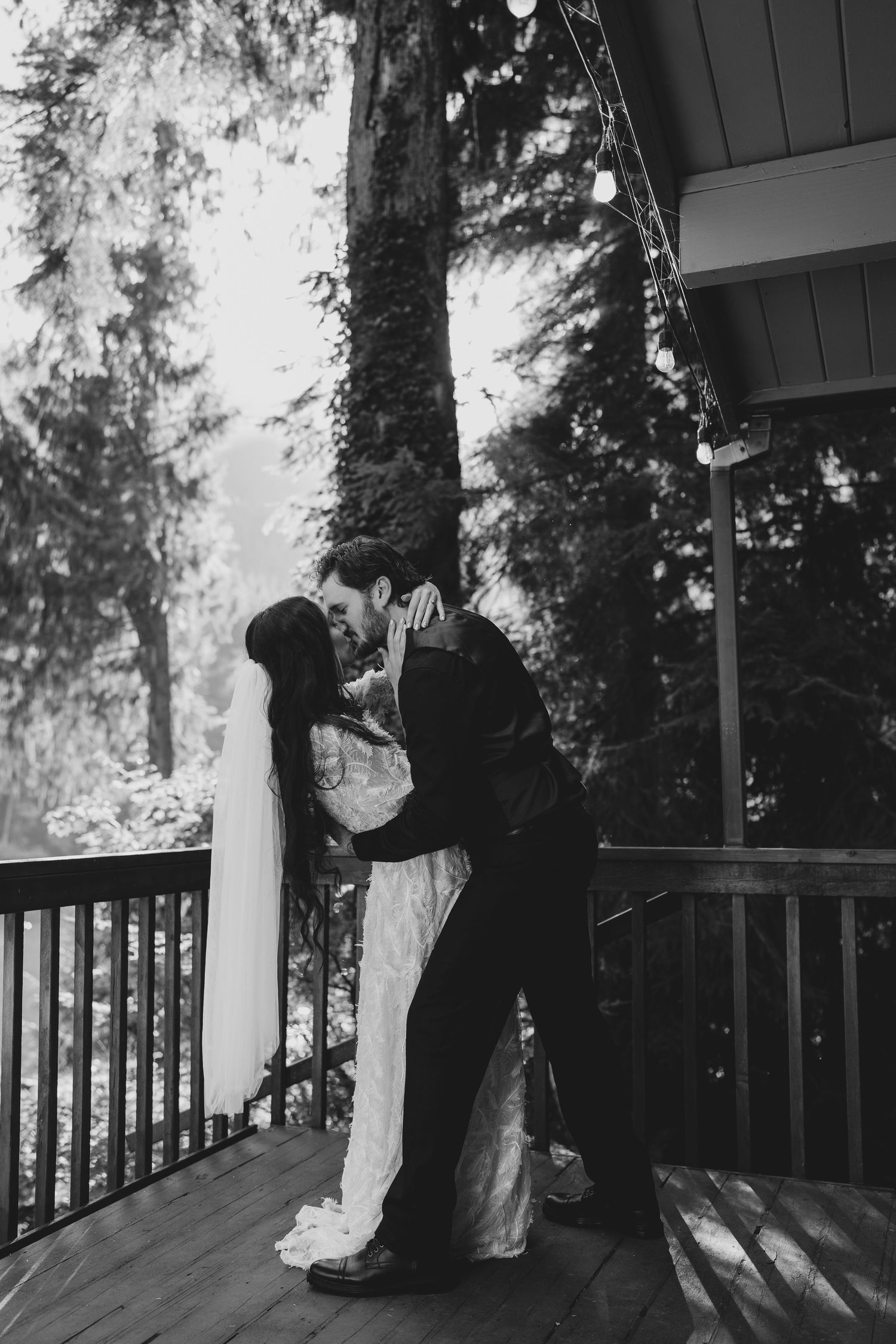 Black and white portrait of newlyweds sharing an intimate moment on a rustic deck.