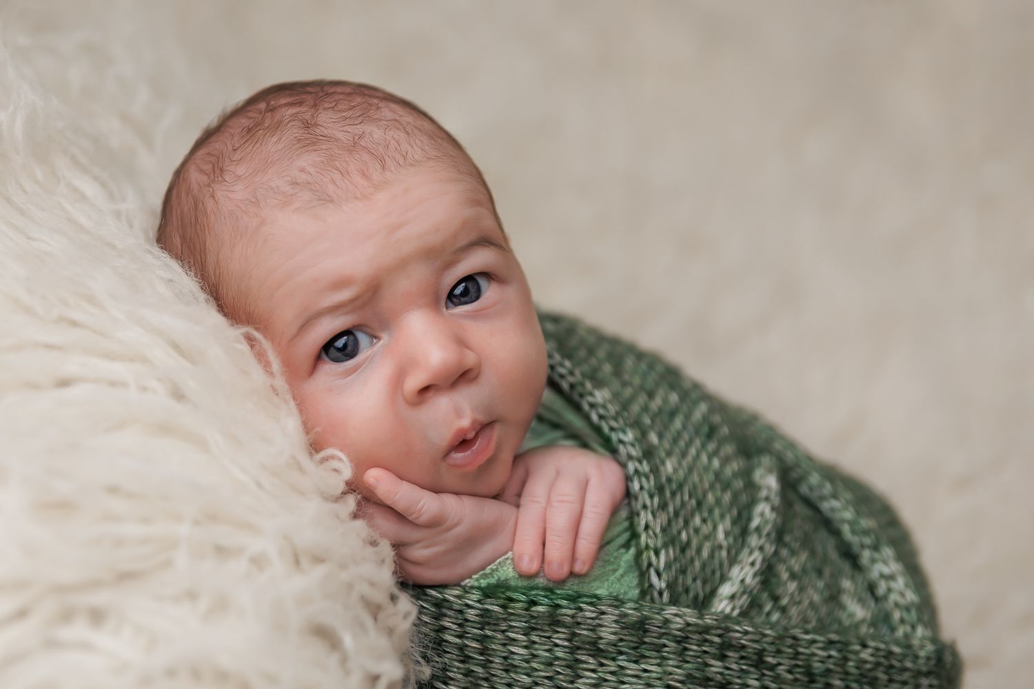 A baby peacefully swaddled in a soft green blanket, exuding warmth and tranquility.