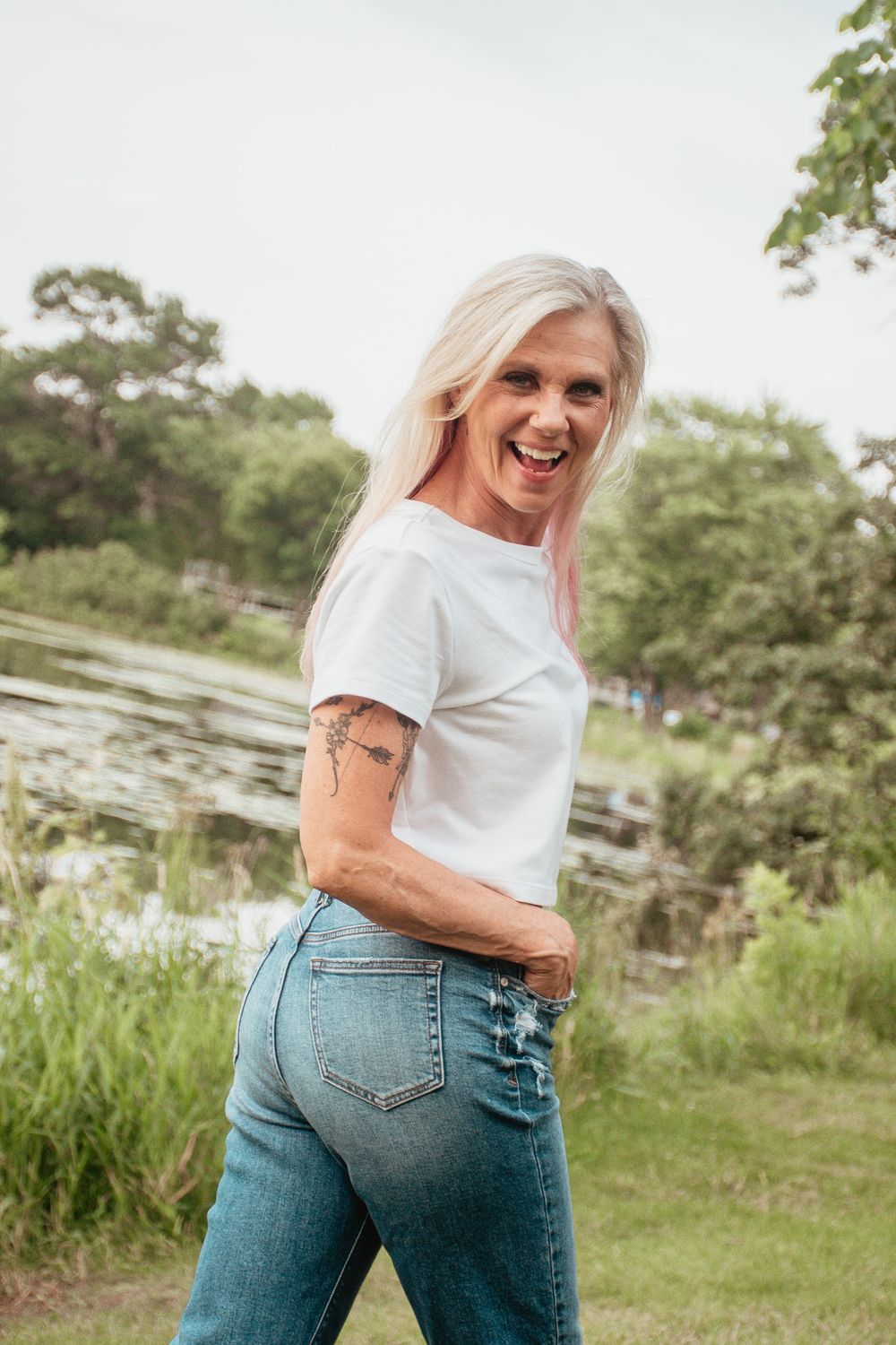 Casual summer portrait by a lake wearing white t-shirt and blue jeans.