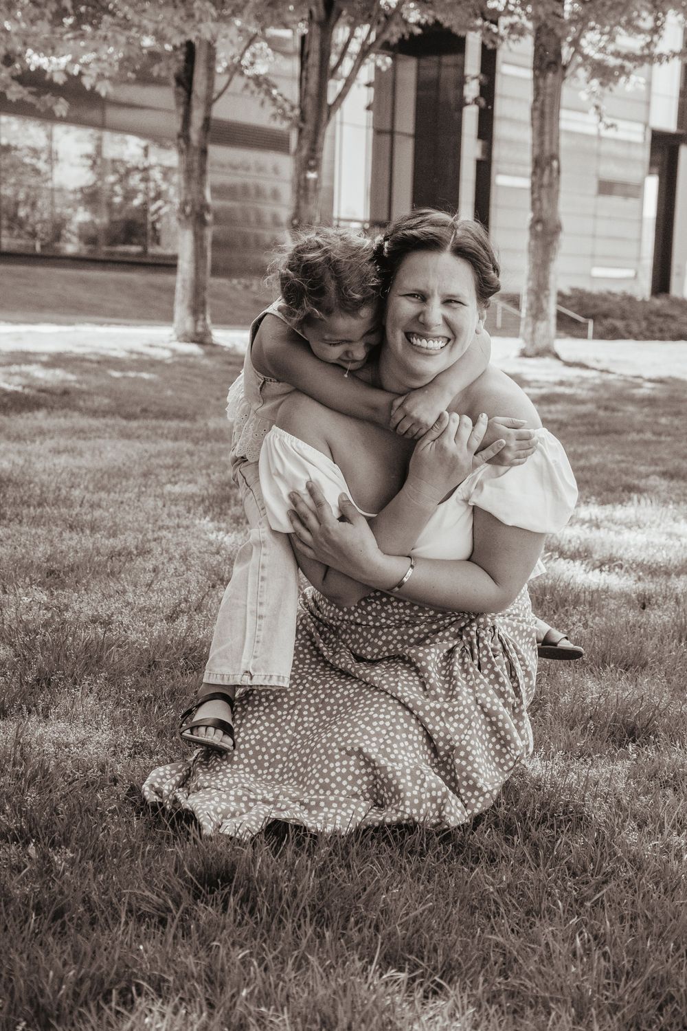 A sweet candid black and white photo showing a joyful embrace on a sunny lawn.