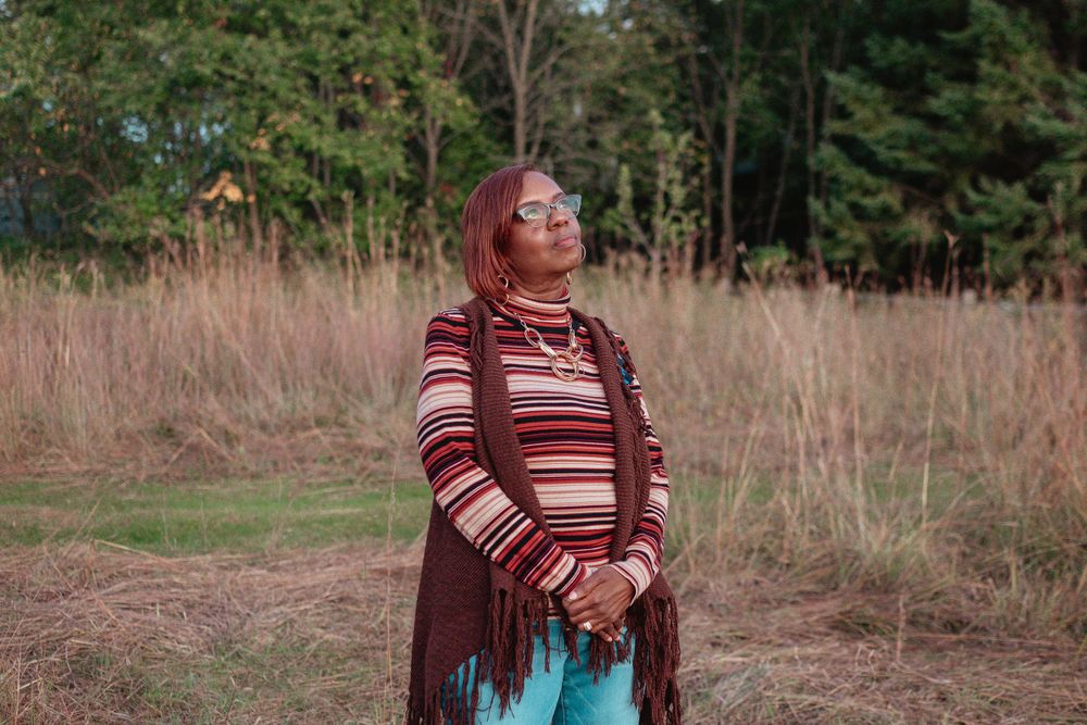 A striped sweater look against a backdrop of tall brown grasses and evergreen trees.