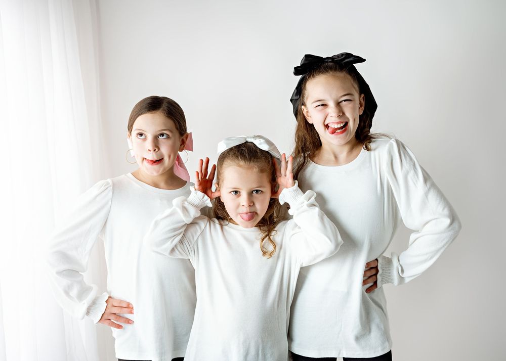 A series of playful and expressive poses against a white background wearing matching white sweaters.