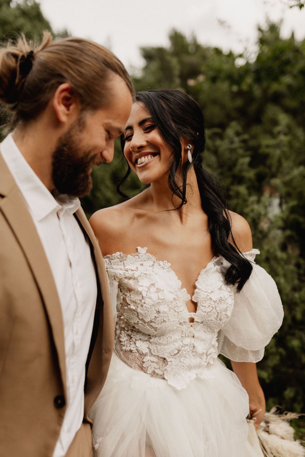 An intimate wedding portrait showing a tender moment between newlyweds outdoors.
