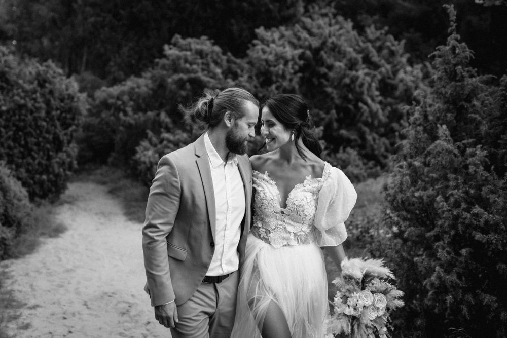 A romantic wedding couple poses on a garden path in black and white photography.