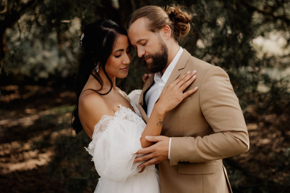 A candid wedding moment captured in warm natural lighting among trees.